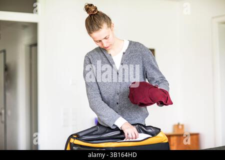 Young woman packing suitcase at home Stock Photo