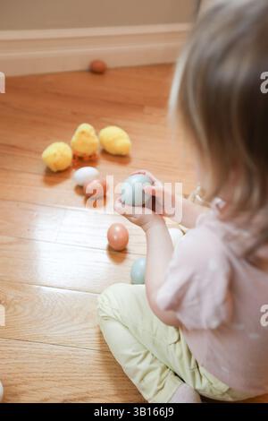 Two year old holding blue chicken egg with easter decoration Stock Photo