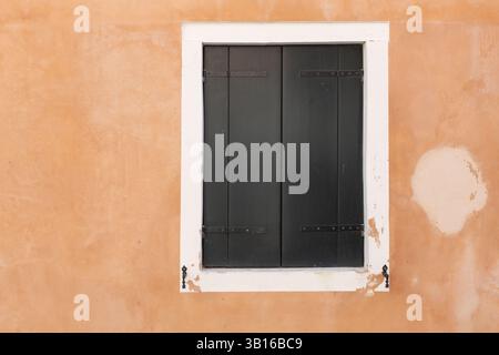 Closed Dark Shutters on Orange Wall Stock Photo