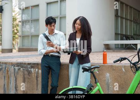 Sustainability and Collaboration. Two young professionals discuss plans while standing near bicycles, highlighting green solutions in an urban context Stock Photo