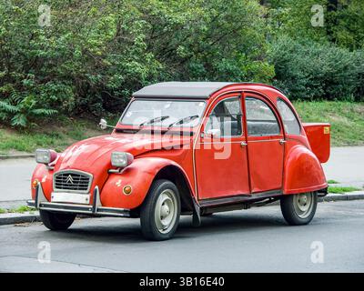 Prague, Czech Republic - August 31 2007: Classic red retro car Citroen 2CV6 parked on urban street with green foliage in background concept of vintage Stock Photo