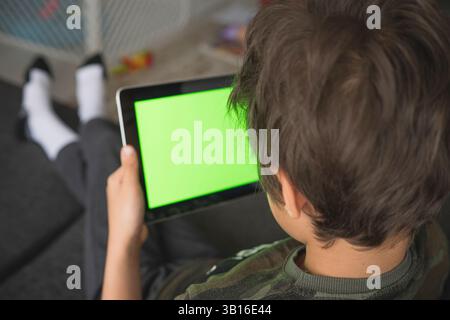 Boy using social media on tablet with chroma key background. touchscreen device for social networks browsing. Stock Photo