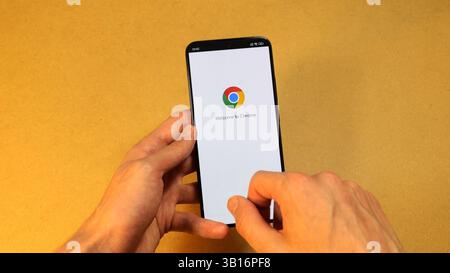 Google Chrome browser system launching on modern smartphone screen mobile phone held in hands, closeup view of welcome screen with logo mobile interne Stock Photo
