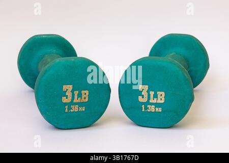 Two blue rubber coated dumbbells on white backgroud. One dumbbell is next to another dumbbell Stock Photo