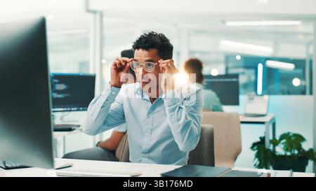 Programmer, research or man with glasses in office for reading code, app development and debugging. Computer, programming and employee with technology Stock Photo