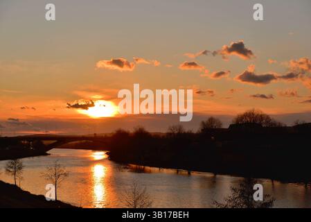Sunset over the Mures river with silhouettes of trees and cumulus clouds in the sky Stock Photo