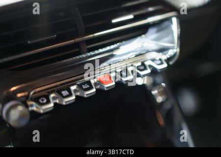 Close-up of a modern car’s hazard button and climate knobs on a textured dashboard, emphasizing user-friendly design and comfort. Stock Photo