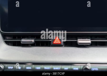 Close-up of a hazard warning button on a car's dashboard vent, emphasizing safety, sleek design, and user-friendly control in a modern vehicle. Stock Photo