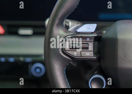 close-up view of a modern steering wheel featuring a textured grip and integrated control buttons, including a prominent drive mode switch. Ideal for Stock Photo