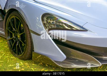 Close-up of a sleek, light blue McLaren sports car's front end, highlighting its headlight, carbon fiber accents, and black alloy wheel. Stock Photo