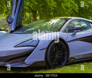 Close-up of a sleek, light blue McLaren sports car's front end, highlighting its headlight, carbon fiber accents, and black alloy wheel, parked on a g Stock Photo