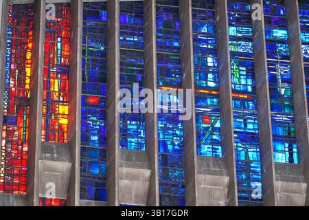 Vibrant stained glass windows illuminate Coventry Cathederal, showcasing a mix of red, blue, and orange hues in an abstract design. Stock Photo