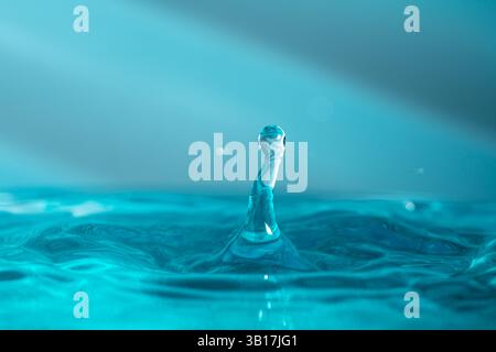 Water droplets fall down closely into the blue water, making it the perfect center in nature Stock Photo