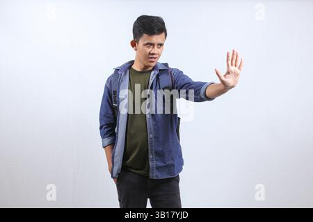 Asian man wearing denim shirt carrying school backpack thinking showing stop gesture isolated on white background Stock Photo