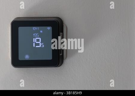 Smart digital thermostat on white wall Stock Photo