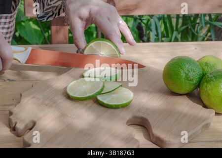 Slicing some limes with a knife on a cutting board. Stock Photo