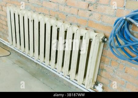 The old cast-iron heating radiator is in place of the new one during the construction of the house. Stock Photo