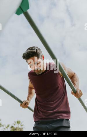 Vertical photo of a fit caucasian man doing dips outdoors. Stock Photo