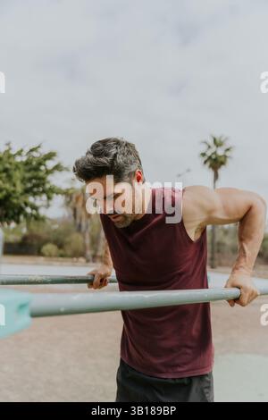 A concentrated man training, doing dips during a workout, vertical photo with copy space. Stock Photo