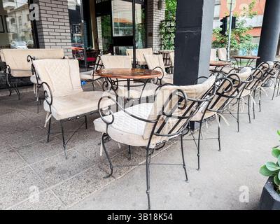 Outdoor cafe terrace with vintage chairs and empty round tables in urban setting. Public leisure and urban coffee culture Stock Photo
