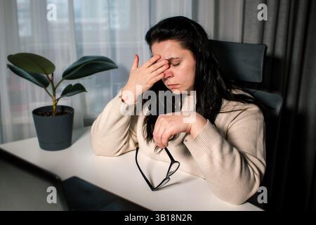 Tired Caucasian woman feeling stressed from work problems. Irritation burnout. Rubbing eyes. Dealing with work deadlines. Have not enough sleep. Stock Photo