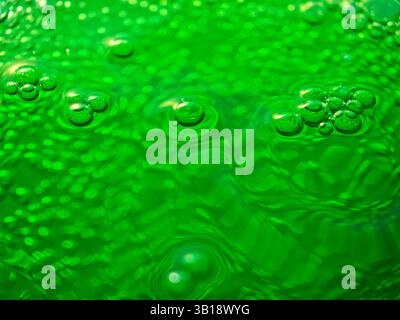 Green bubbly liquid surface forming concentric circles and reflecting light Stock Photo