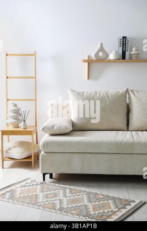 Comfortable sofa with pillows and different decor in room. Interior design Stock Photo