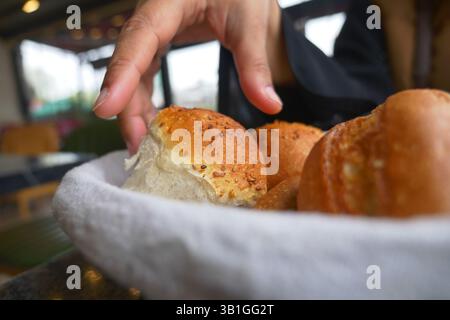 Hand reaching for freshly baked bread rolls in cozy cafe Stock Photo