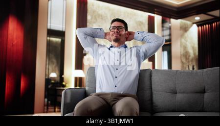 Happy Man Sitting On Sofa Thinking In Hotel Stock Photo