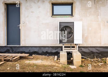 Installing heat pump on a wall of new family house Stock Photo