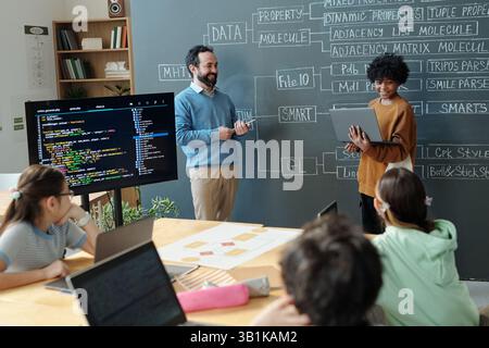 Teacher Explaining Programming Concepts to Engaged Students Stock Photo