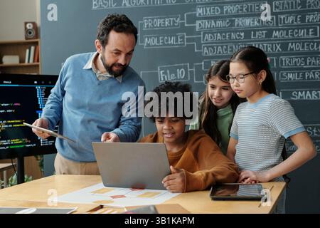 Teacher Engaging Students in Computer Class With Laptops Stock Photo