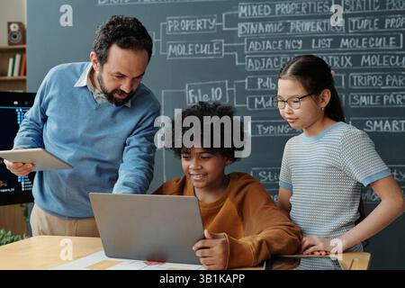 Educator Assisting Students During Class Presentation Stock Photo
