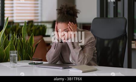 Exhausted businesswoman tired overworked employee in office suffer fatigue hard work finish online computer working close laptop relax rest hold head Stock Photo