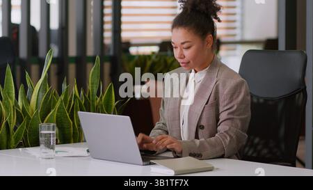 Serious ethnic woman African American girl businesswoman female employer broker agent lady business worker manager look at laptop pc screen work Stock Photo