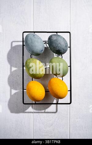 Easter eggs drying on a cooling rack after being naturally dyed with hibiscus and turmeric, creating a beautiful display of yellow and green hues, rea Stock Photo