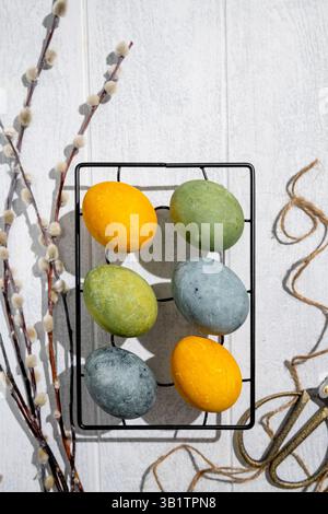 Easter eggs drying on a cooling rack after being naturally dyed with hibiscus and turmeric, creating a beautiful display of yellow and green hues, rea Stock Photo