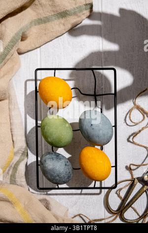 Easter eggs drying on a cooling rack after being naturally dyed with hibiscus and turmeric, creating a beautiful display of yellow and green hues, rea Stock Photo