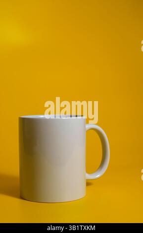Minimalist white coffee mug placed on a bold yellow background with space for text or branding. Stock Photo