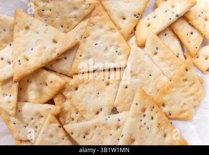 close up crispy triangular crackers top view. Dietary cereal with salt and poppy seed Stock Photo
