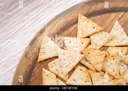 close up crispy triangular crackers top view. Dietary cereal with salt and poppy seed Stock Photo