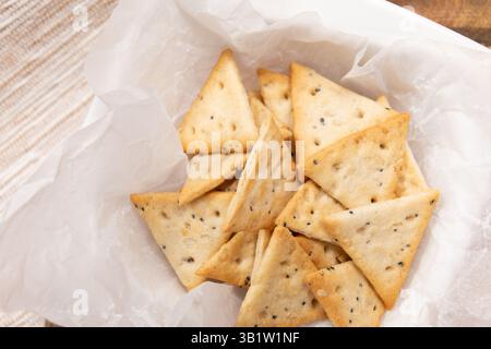 close up crispy triangular crackers top view. Dietary cereal with salt and poppy seed Stock Photo