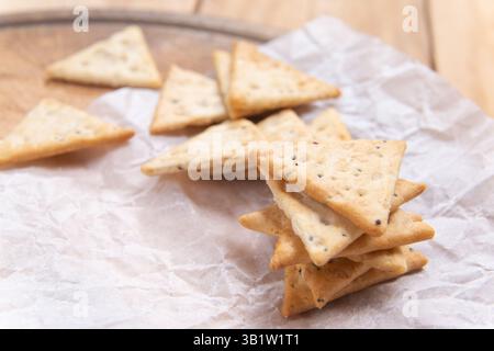 close up crispy triangular crackers top view. Dietary cereal with salt and poppy seed Stock Photo