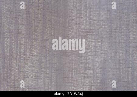 Close-up of beige semi-transparent linen curtain fabric with woven grid texture. Minimalistic textile pattern. Interior and home decor concept. Stock Photo