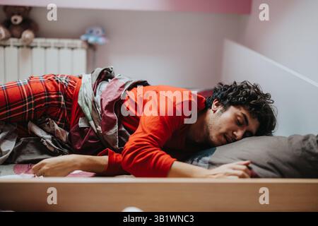 Young man sleeping peacefully in cozy bed wearing red pajamas Stock Photo