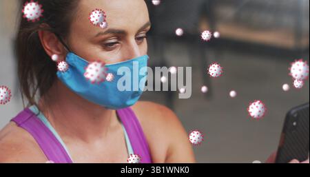 Checking adult woman wearing blue cloth mask scrolling smartphone in gym Stock Photo