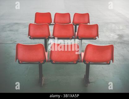 Three Rows Of Three Uncomfortable Orange Plastic Chairs In A Waiting Area Stock Photo