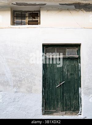 White wall of an old building with green painted wooden door Stock Photo