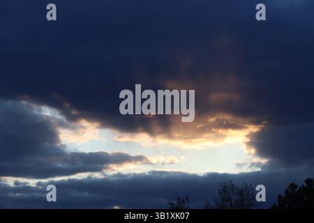 Crepuscular rays coming from a gap in the clouds during sunset Stock Photo