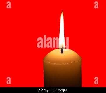 A single burning candle flame or light glowing on a big white candle is isolated on red background with clipping path. Stock Photo